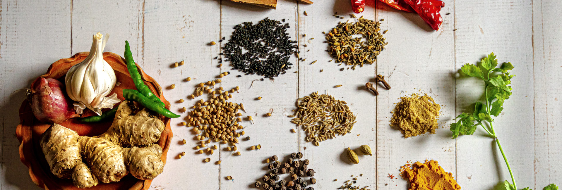 Raw curry spices including garlic, ginger, cloves, and chillies.