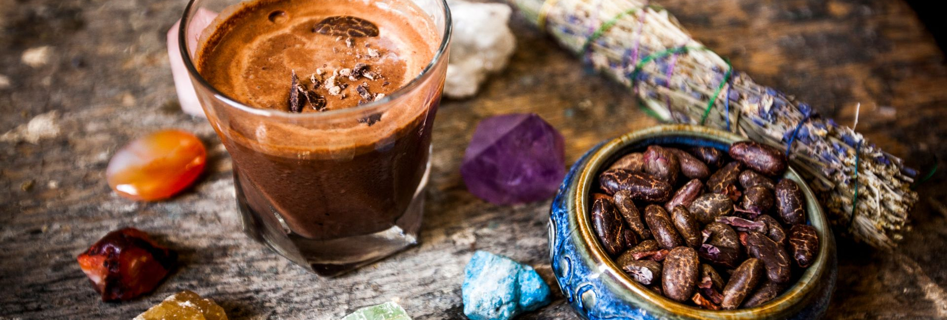 Cacao beans in blue bowl next to glass of cacao.