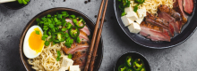 Ramen noodles in bowls with egg and pork, plus chopsticks