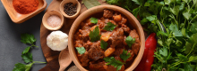 Pot of goulash surrounded by herbs and spices