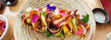 Beautifully plated dish of fruit shavings with edible flowers
