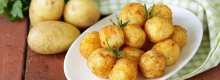 Raw and cooked potatoes on a wooden table