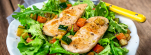 Grilled chicken breasts on a bed of salad