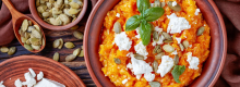 Pumpkin mash in a bowl adorned with feta cheese and basil leaves