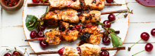 Marinated chicken sosaties on white plate with cherries