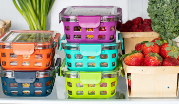 Various food containers containing fresh produce, on a fridge shelf.