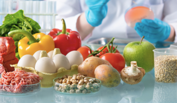 Fresh fruit and meat in the foreground on a table in a chemistry lab