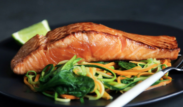 Fish with vegetables and a lemon on a plate.