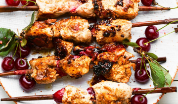 Marinated chicken sosaties on white plate with cherries